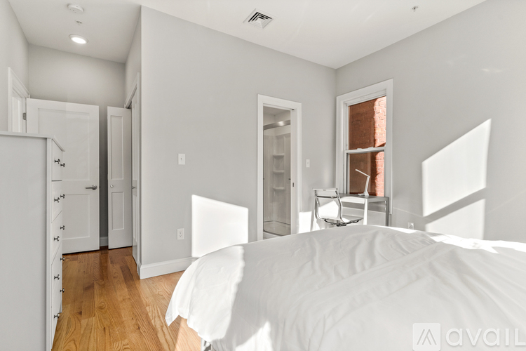 A bedroom with a large bed and a wooden floor.