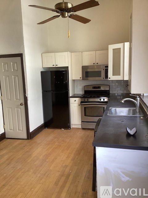 A kitchen with a black fridge and a black counter top.