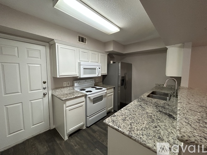 A kitchen with white cabinets and granite countertops.