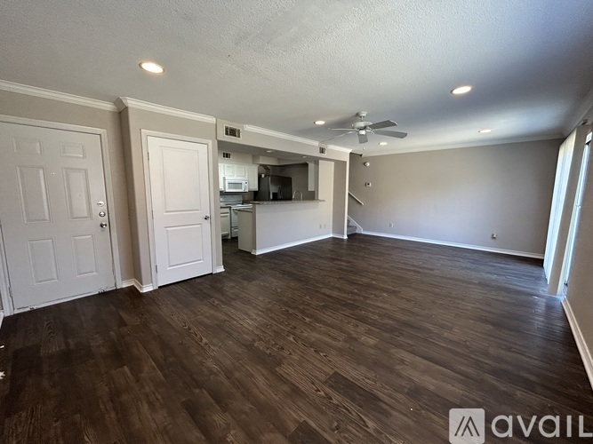 A spacious room with wooden flooring and a ceiling fan.