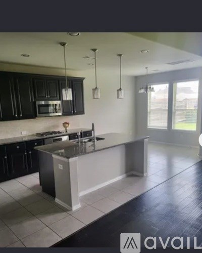 A kitchen with black cabinets and a white island.