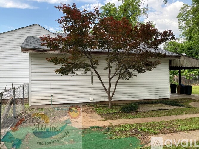 A tree with red leaves is in front of a white garage.