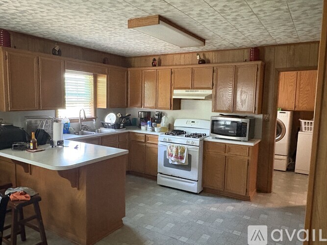 A kitchen with wooden cabinets and a white stove top oven.