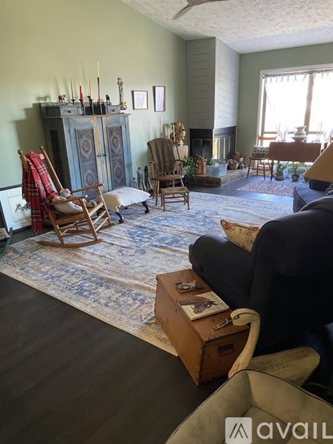 A living room with a blue rug and a wooden rocking chair.