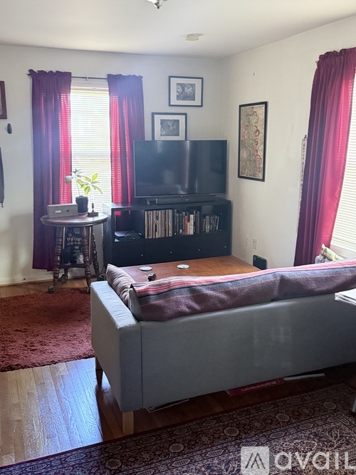 A bedroom with a bed, a table, a television, and a bookshelf.