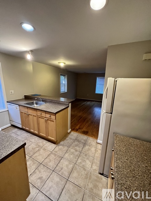 A kitchen with a white refrigerator, wooden cabinets, and a granite countertop.