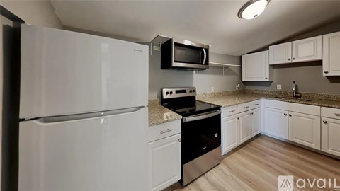 A kitchen with white appliances and wooden floors.