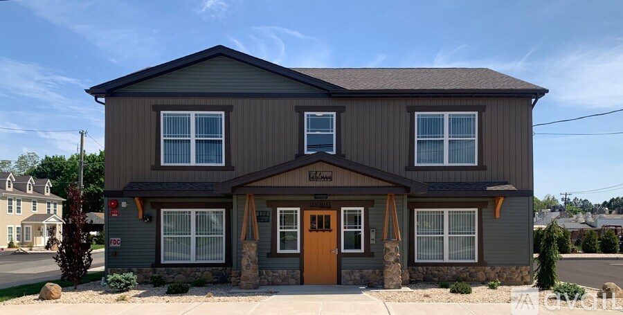 A grey house with a brown door and windows.