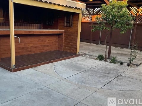 A wooden garage with a brown fence and a tree in front.