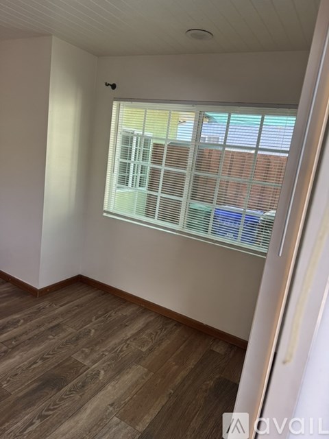 A room with wooden flooring and a window on the right side.