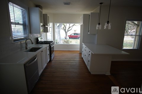 A kitchen with white cabinets and a wooden floor.