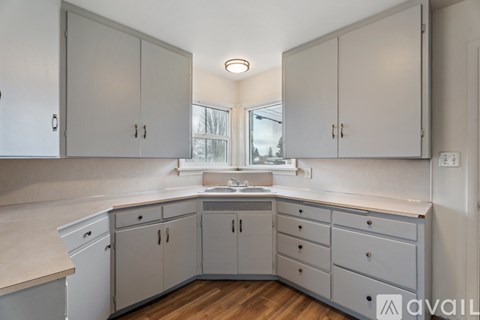 A kitchen with white cabinets and a wooden floor.