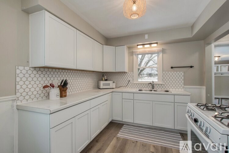 A kitchen with white cabinets and a white tiled backsplash.