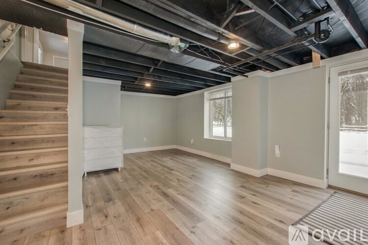 A room with wooden floors and a staircase on the left side.