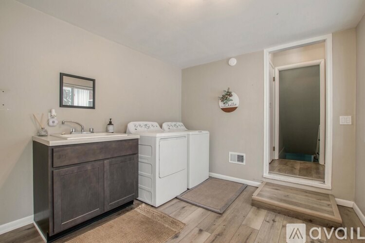A bathroom with a white washer and dryer, a wooden cabinet, and a rug on the floor.