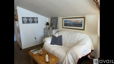 A living room with a white couch and a wooden coffee table.