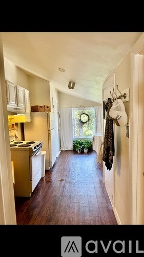 A kitchen with a stove top oven and a wooden floor leading to a door.