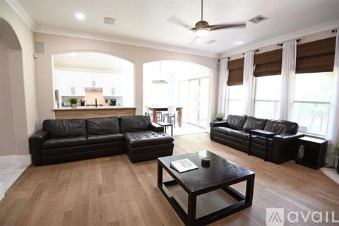 A living room with black leather furniture and wooden flooring.