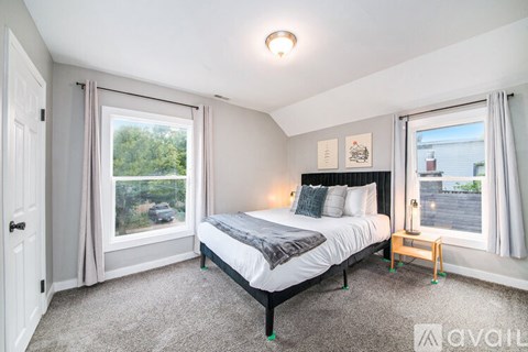 A bedroom with a large bed and a window overlooking a green area.