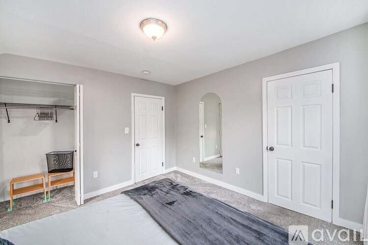 A bedroom with a bed, a bench, and a wardrobe.