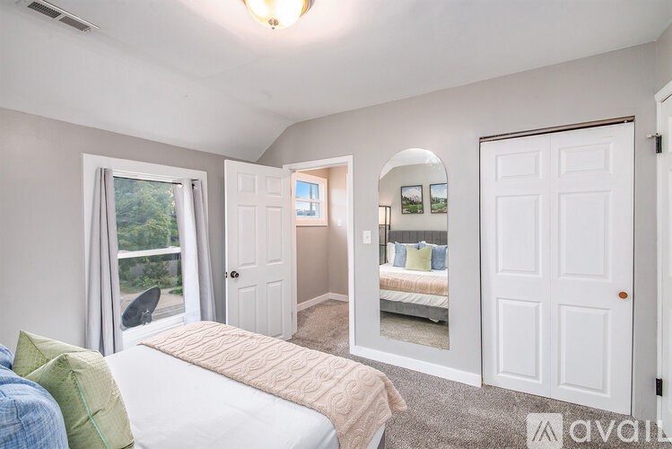 A bedroom with a large bed and a window with a view of trees.