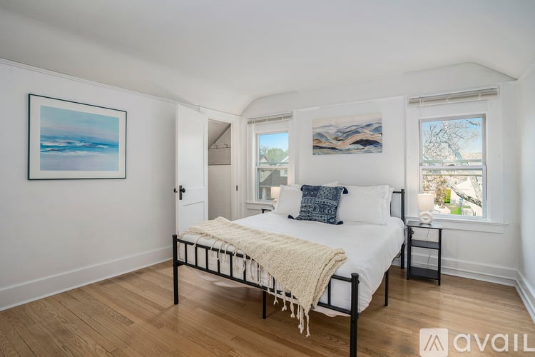 A bedroom with a bed, a nightstand, and a window.