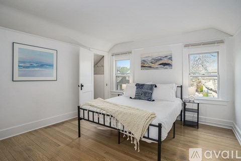 A bedroom with a bed, a nightstand, and a window.