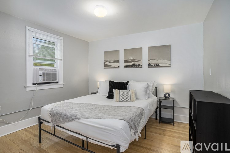A bedroom with a bed, nightstand, and pictures on the wall.