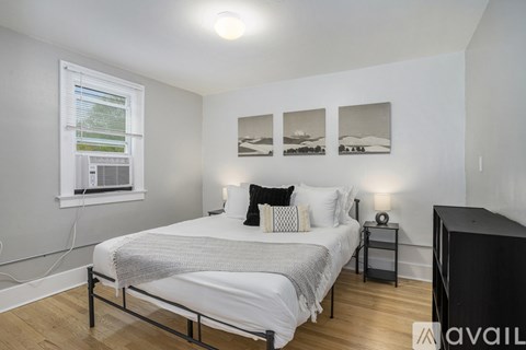 A bedroom with a bed, nightstand, and pictures on the wall.