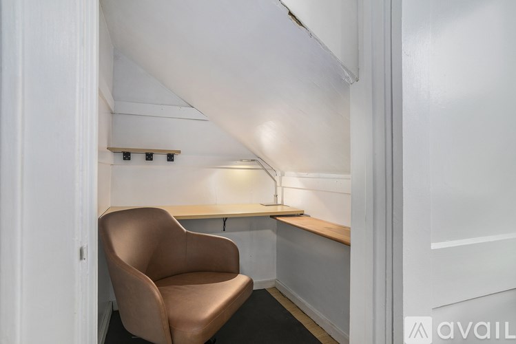 A brown chair is in a white room with a desk and a light on.