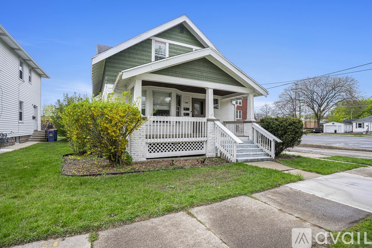 A house with a green roof and white walls is for sale.