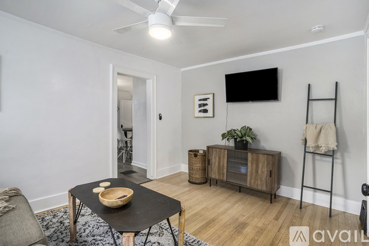 A living room with a black table, a TV, a plant, and a ladder.
