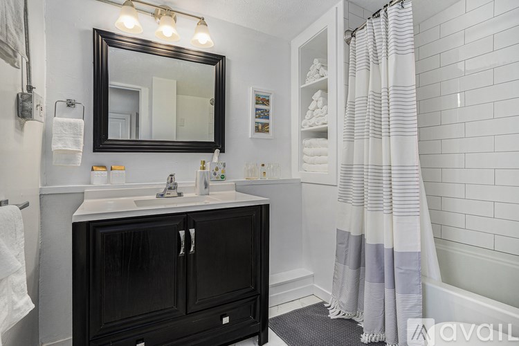 A bathroom with a black cabinet and a white sink.