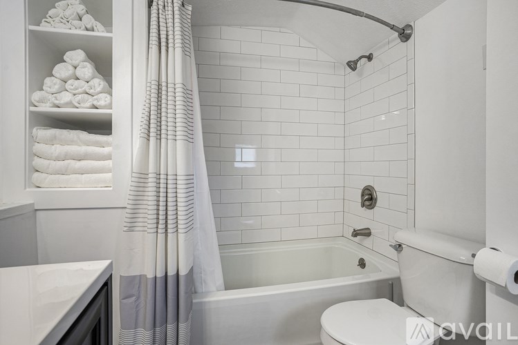 A white bathroom with a towel shelf, shower, and toilet.
