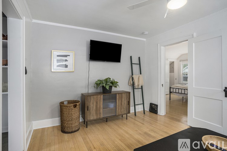 A room with a flat screen TV mounted on the wall above a wooden cabinet with a potted plant on top.