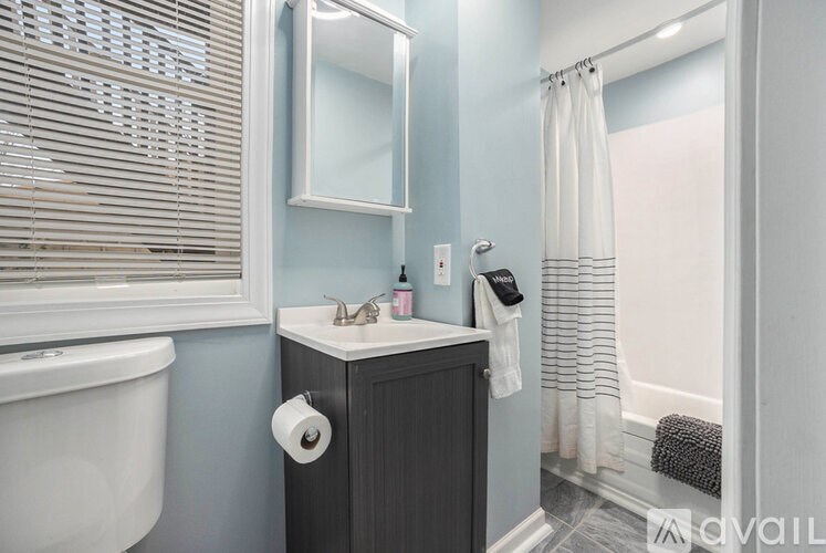 A bathroom with a white tub, sink, and toilet paper roll.