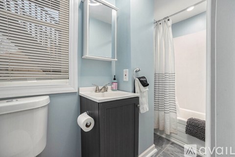 A bathroom with a white tub, sink, and toilet paper roll.