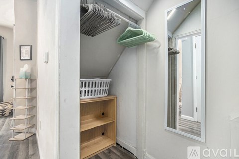 A white closet with a mirror and a basket on the shelf.