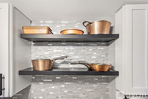 A kitchen with two shelves containing copper pots and pans.