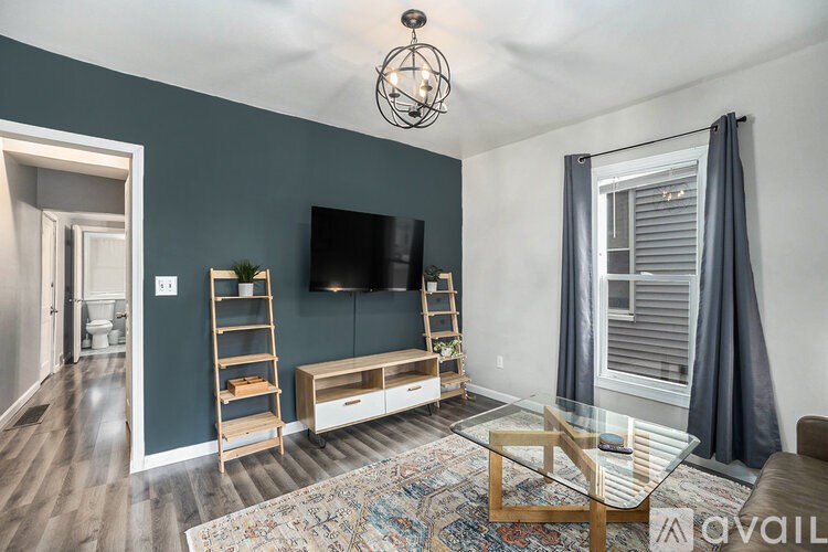 A living room with a television, a glass table, and a rug.