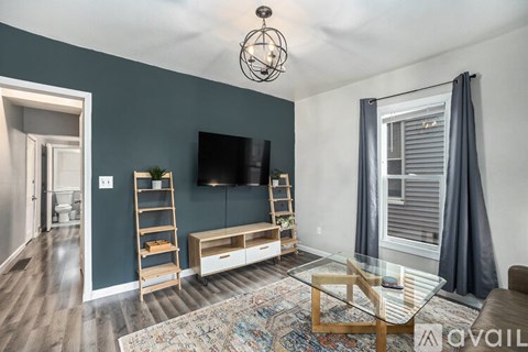 A living room with a television, a glass table, and a rug.