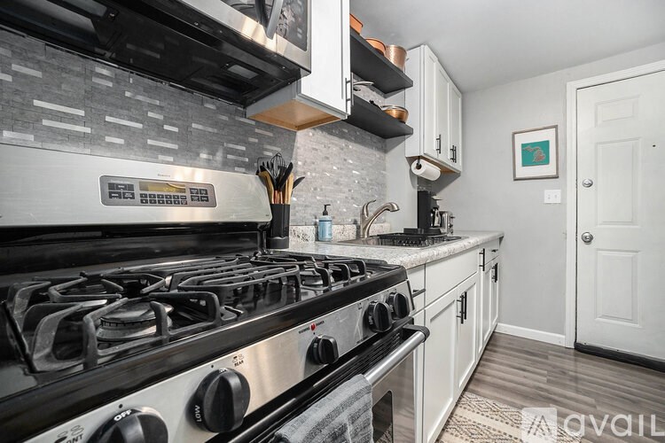 A modern kitchen with a stainless steel gas stove and white cabinets.