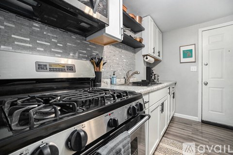 A modern kitchen with a stainless steel gas stove and white cabinets.