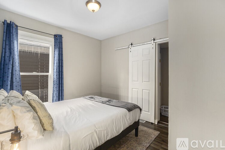 A bedroom with a bed, pillows, and a window with blue curtains.