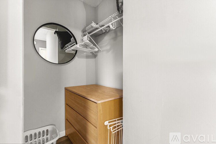 A round mirror hangs on a wall above a wooden dresser.