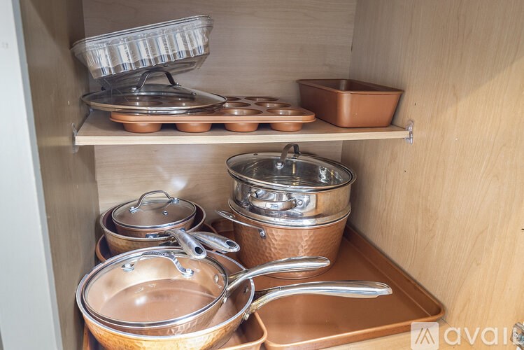 A kitchen cabinet with various pots and pans.