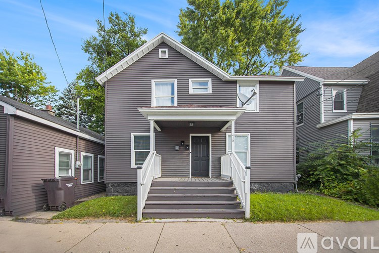 A house with a front yard and a tree in the background.