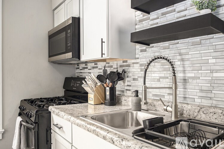 A kitchen with a black microwave above the stove and a white sink.