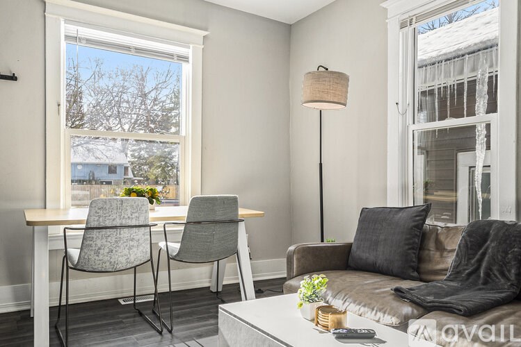 A living room with a grey couch, a table with two chairs, and a floor lamp.