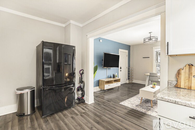 A kitchen with a black fridge and a TV on the wall.